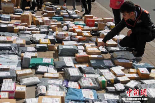 资料图:山西太原一高校外,学生们在地摊上找寻各自的快递。武俊杰 摄 点击进入下一页