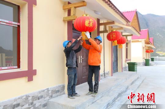 搬迁工作人员为房屋挂上红灯笼 钟欣 摄