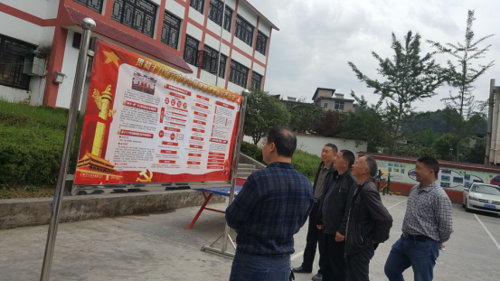农民党员在宣教月宣传展板上学习党风廉政建设知识