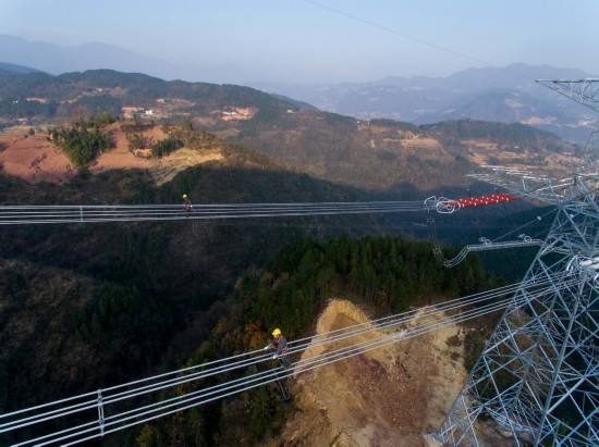 12月6日，国网重庆电力检修公司的技术人员在高空进行特高压线路验收。  新华社记者 刘潺 摄