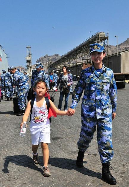 2015年3月，也门，海军女战士牵着一名小女孩的手准备登上军舰。