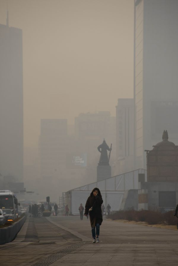 资料图片： 2014年2月25日，一名女子在韩国首尔街头掩面而行。当日韩国首尔遭遇雾霾天气。 新华社/法新