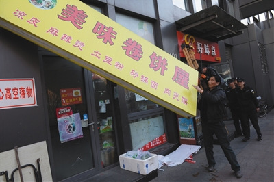 昨日下午，丰台区食药监局执法人员对涉嫌违法经营的店铺招牌进行拆除。新京报记者 吴江 摄