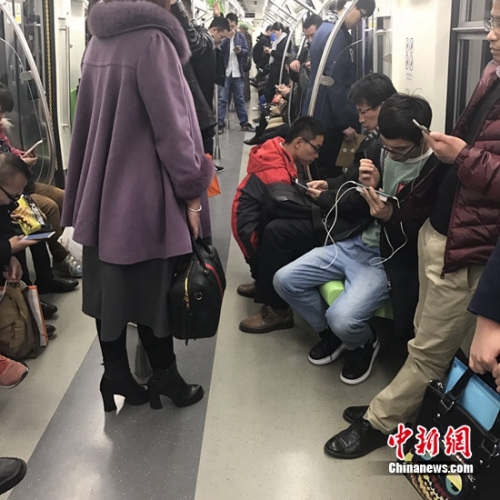 资料图：北京地铁14号线，一些人在低头看手机。张曦 摄