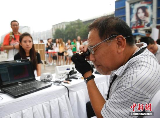 资料图：在北京崇文门街边举行的寺库奢侈品鉴宝会，吸引众多路人排队鉴宝。 <a target='_blank' href='http://www.chinanews.com/'>中新社</a>发 杜洋 摄