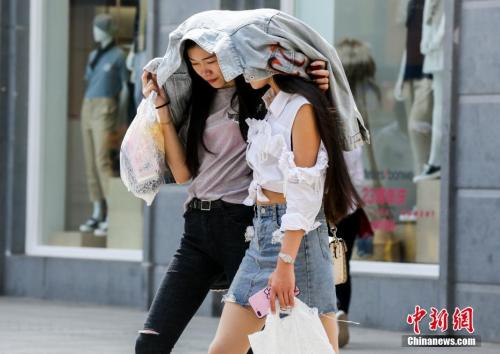 4月3日，武汉江汉路步行街上，两名年轻女性用外套遮挡火辣的阳光。当日，武汉主城区最高气温已达30摄氏度。 <a target='_blank' href='http://www.chinanews.com/'>中新社</a>记者 张畅 摄