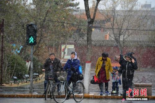 4月3日，民众在雪中步行过马路。当日，呼和浩特迎来降雪，气温骤然下降，不少民众纷纷加衣保暖。<a target='_blank' href='http://www.chinanews.com/'>中新社</a>记者 刘文华 摄