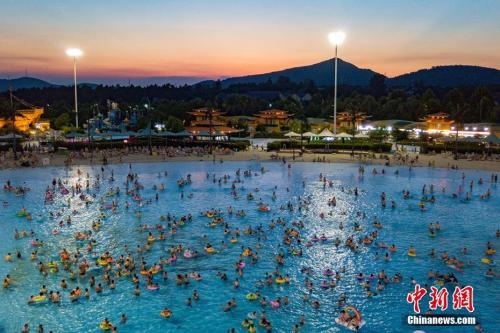 7月13日，为躲避持续高温闷热的天气，大批南京民众在夜色中涌进水上乐园戏水。泱波 摄