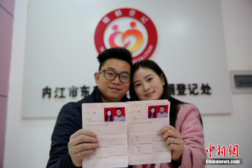 资料图：2016年2月14日，在四川省内江市东兴区婚姻登记处，一对新人在展示刚领取的结婚证书。兰自涛 摄