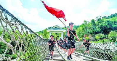 参加军事夏令营的学生在位于南京溧水的国防园里的“缩微版长征”中“四渡赤水”。新华社发