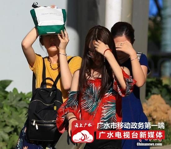 7月20日，武汉高温持续，出行的市民用手和随身物品遮挡阳光。中新社记者 张畅 摄