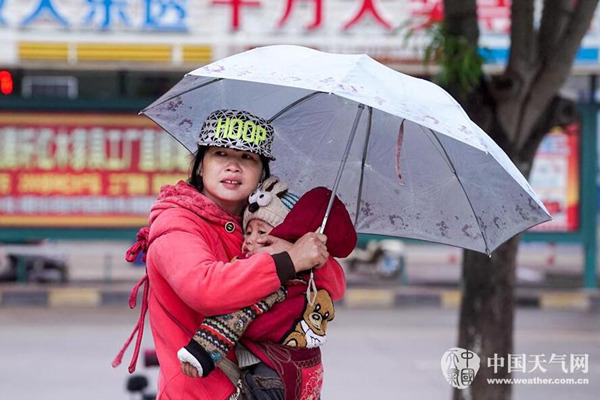 9日8时，广西钦州城区气温13.3℃，怀抱小孩的母亲冒雨出行。（图/李斌喜）