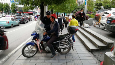 摩托车乱停人行道阻碍通行成顽疾 城管队员不厌其烦清理