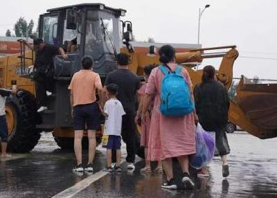 直击河南卫辉街头：道路积水超半米 铲车当“公交”运送居民