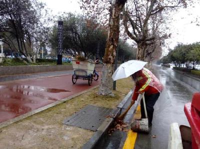 环卫工人冒雨作业 成马路靓丽风景
