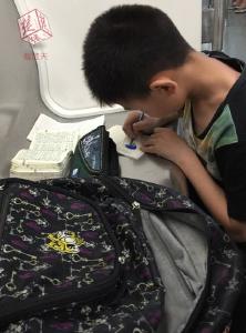 小男孩趴地铁车厢写作业 乘客拍照点赞称一股清流